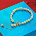 Women's bracelet with a round Hetian jade bead, pearl pendant, and gold-colour alloy clasp.