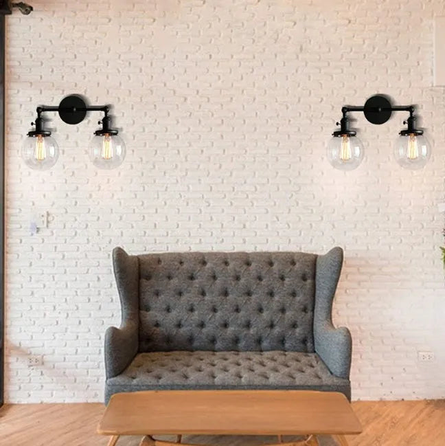 Double headed black iron wall lamp with spherical glass shades on a wall