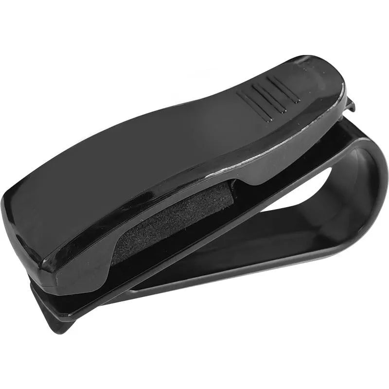 Black plastic clip for car sunshade holding sunglasses and a ticket.