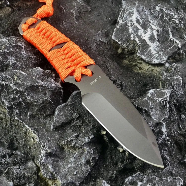 Straight blade outdoor survival knife with binding rope handle next to ABS plastic sheath