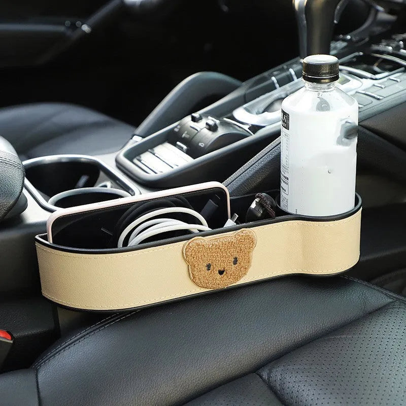 Leather car seat gap storage box with a cartoon bear design, shown hanging between vehicle seats.