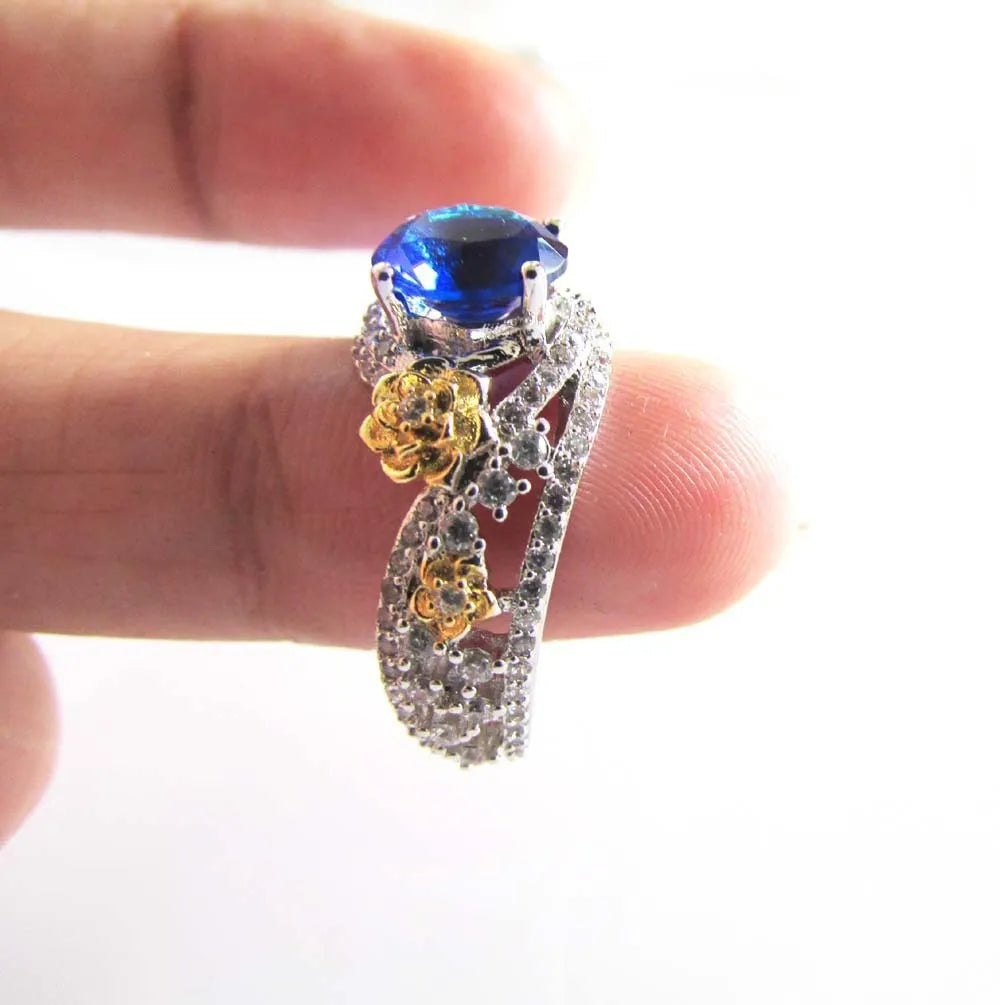 Flower rose two-tone copper ring for women with blue artificial gemstone on a white background