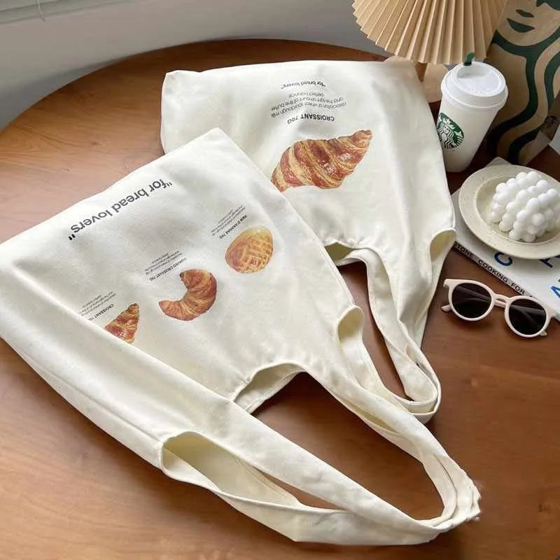 Beige canvas tote bag with croissant-shaped shoulder design and wide 44cm structure