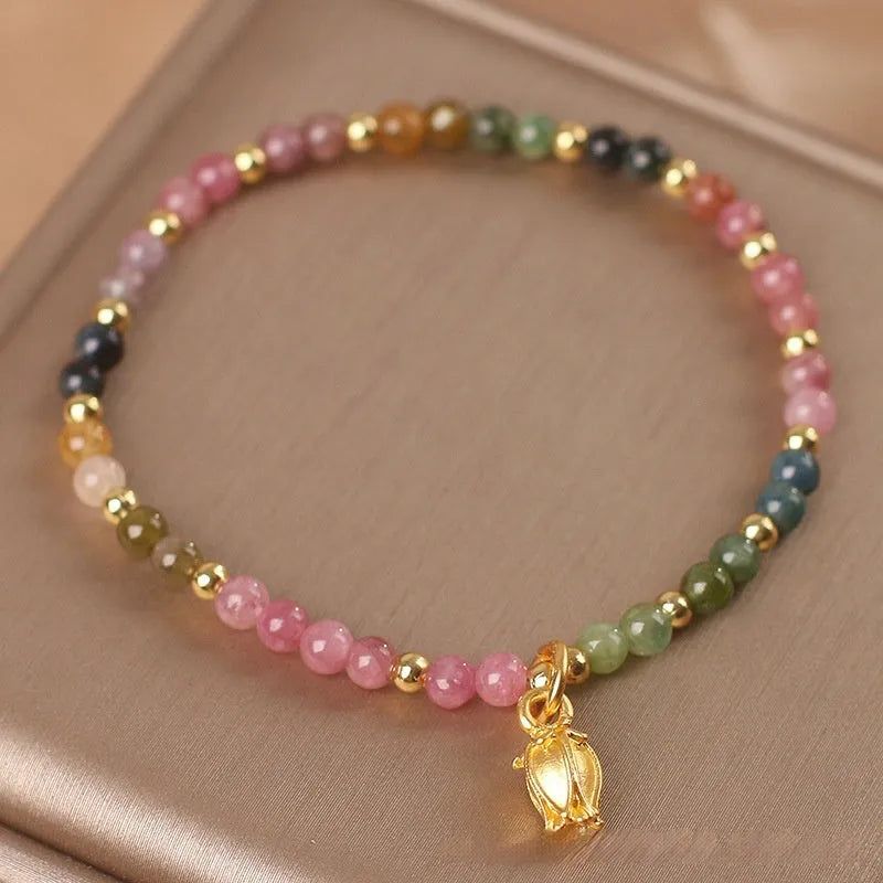 Natural tourmaline beaded anklet with a floral charm, shown being worn.