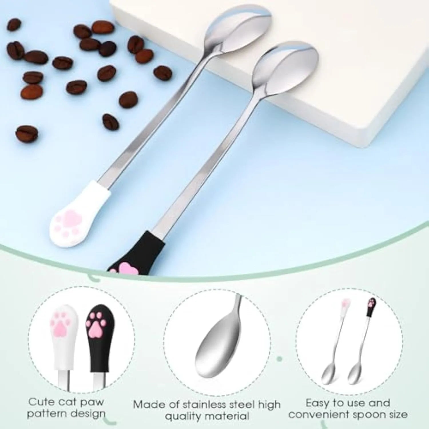 White and black stainless steel pet food spoons with silicone cat paw print handles on a table.