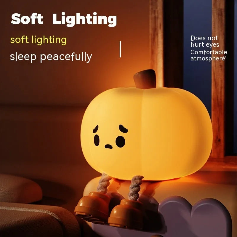 Pumpkin-shaped silicone night light with soft orange glow on wooden bedside table