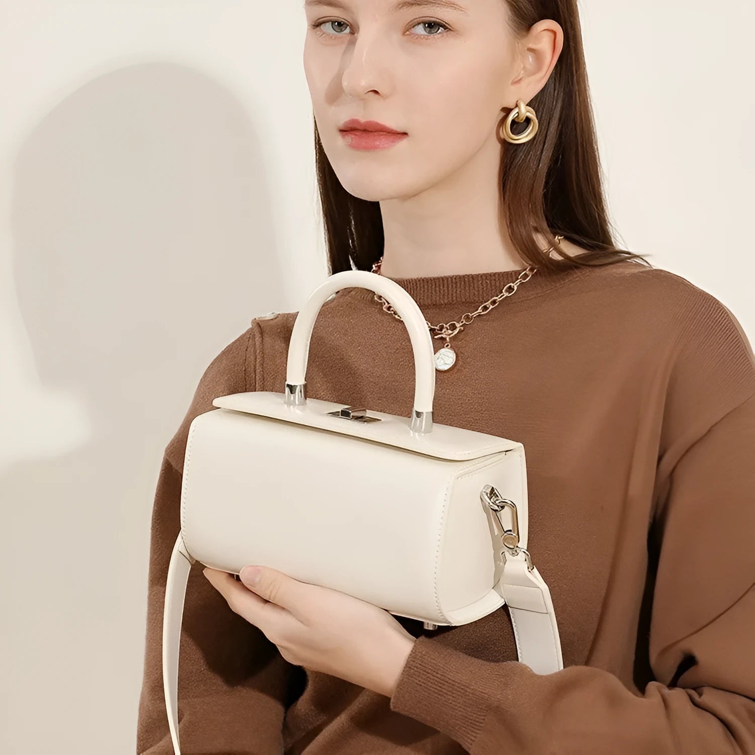 Brown leather women's crossbody bag with a single shoulder strap and clamshell opening.