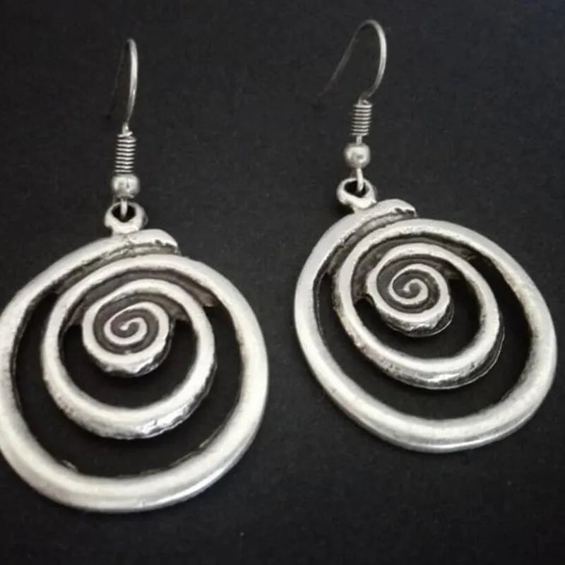 A pair of silver geometric spiral statement earrings with a distressed metal finish.