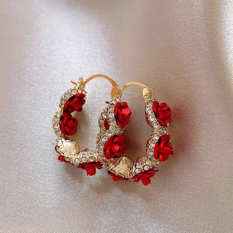 A pair of red flower-shaped alloy clip-on earrings with rose detailing for women.