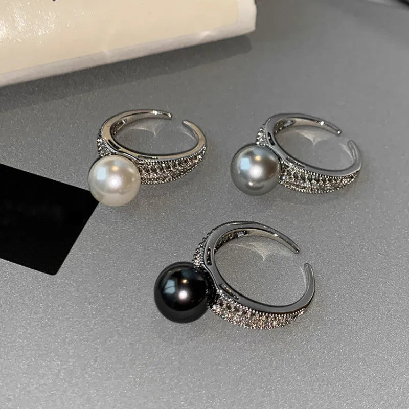 Silver-tone adjustable open ring with a geometric shape and a single black pearl on a model's finger.