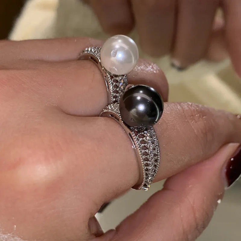 Silver-tone adjustable open ring with a geometric shape and a single black pearl on a model's finger.