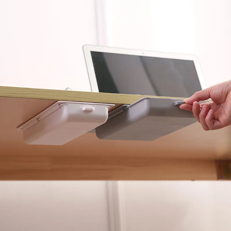 White adhesive under-table storage drawer with grid pattern mounted beneath a wooden desk.