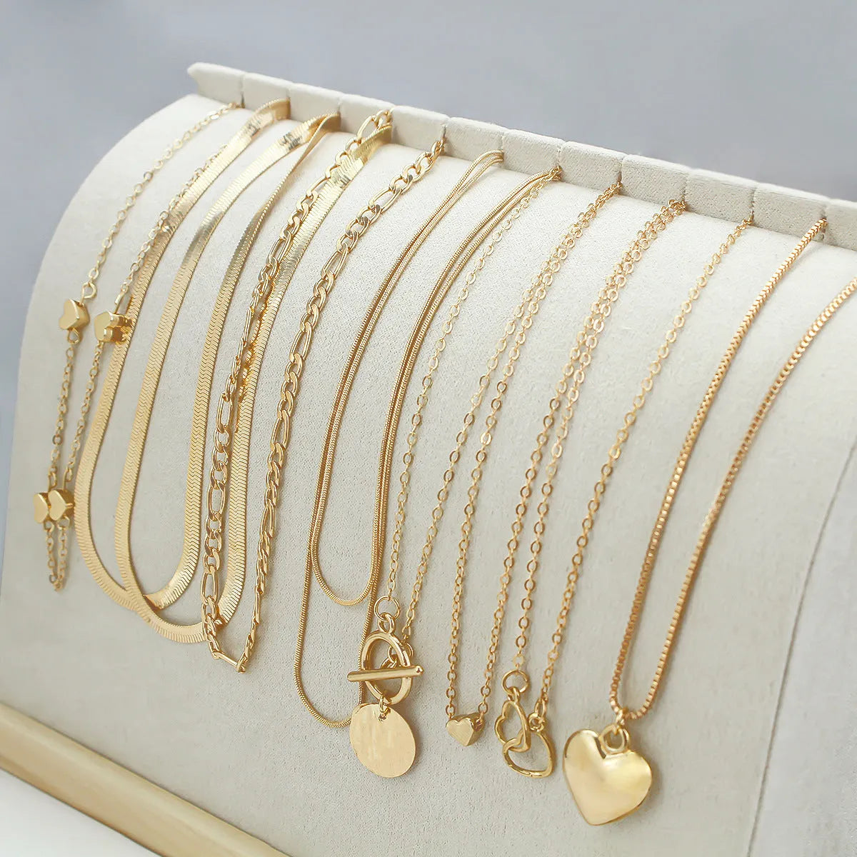 Gold electroplated women's necklace suit with ten pieces showing alloy pendants on snake bone chains