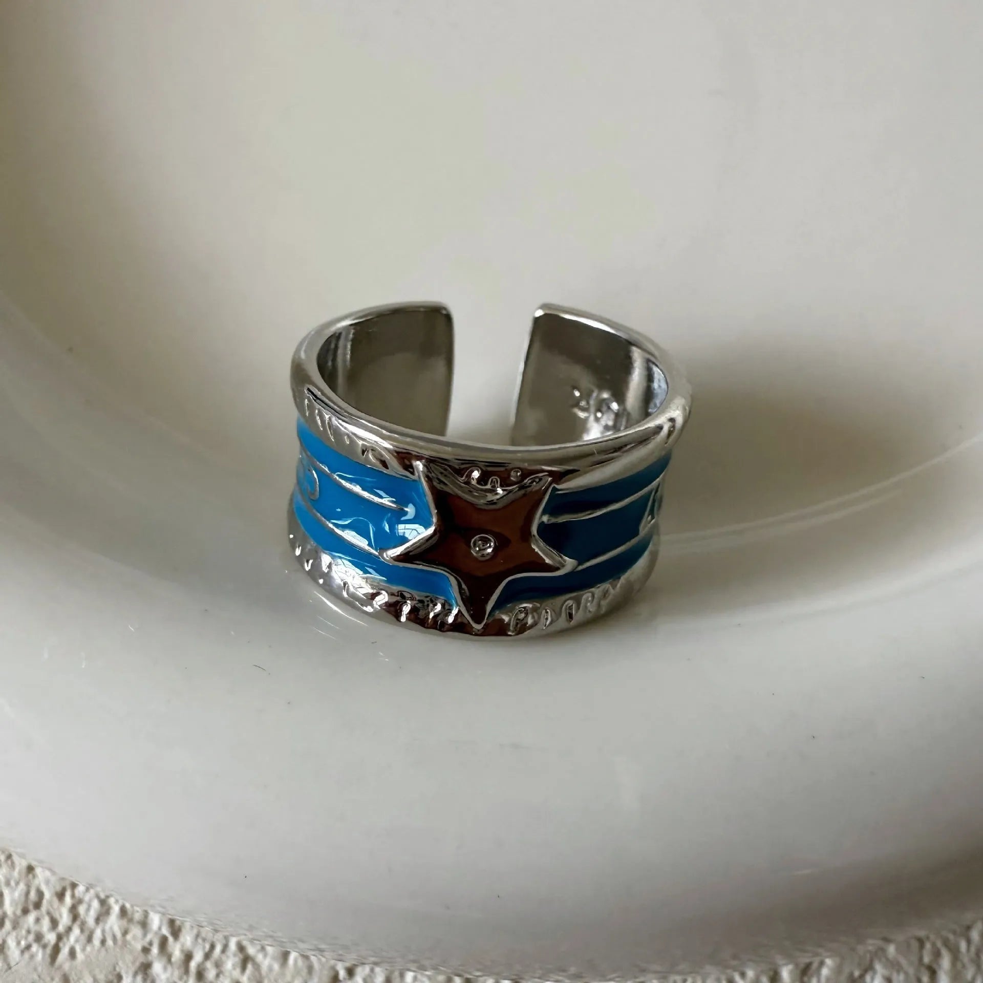 Adjustable geometric ring in distressed electroplated copper on a hand, showing colour options.