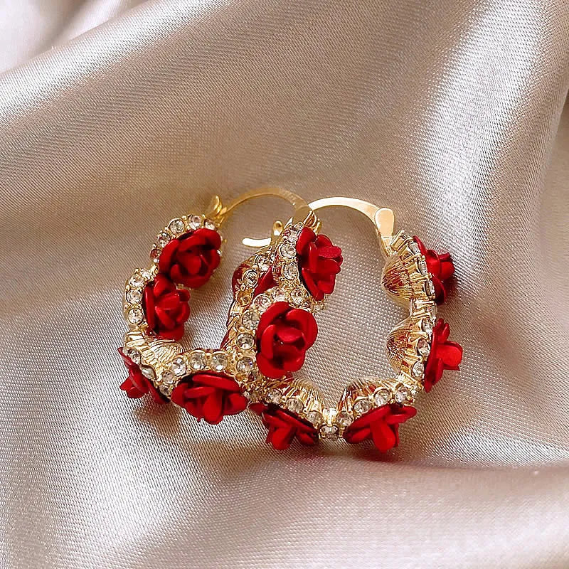A pair of red flower-shaped alloy clip-on earrings with rose detailing for women.