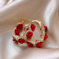 A pair of red flower-shaped alloy clip-on earrings with rose detailing for women.