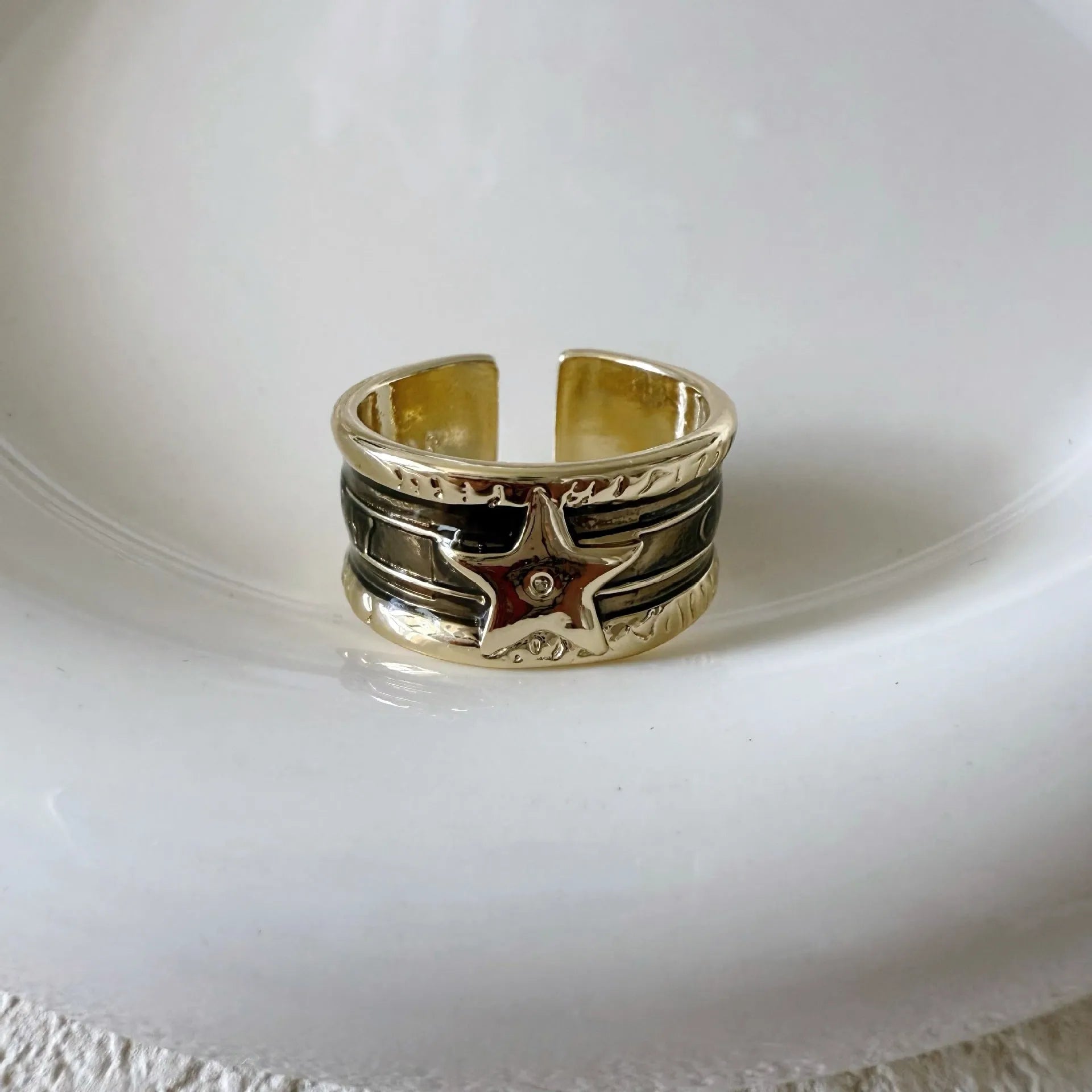 Adjustable geometric ring in distressed electroplated copper on a hand, showing colour options.
