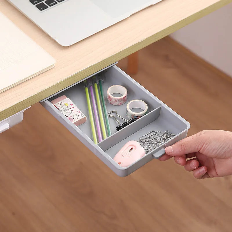 White adhesive under-table storage drawer with grid pattern mounted beneath a wooden desk.