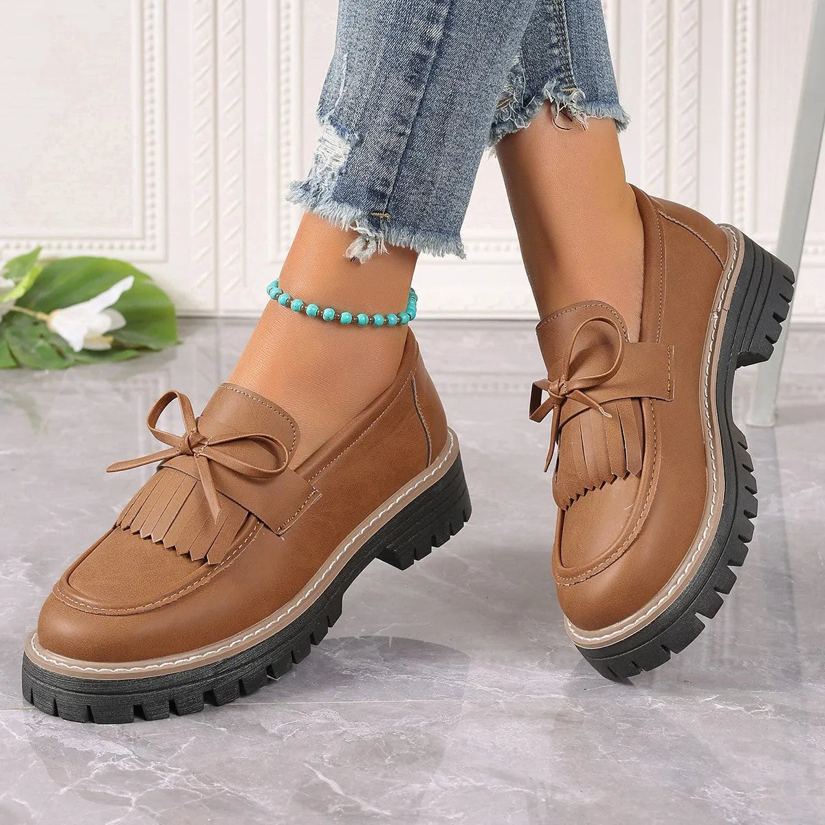 Black plus-size women's loafers with a bow and tassel decoration on the round toe.
