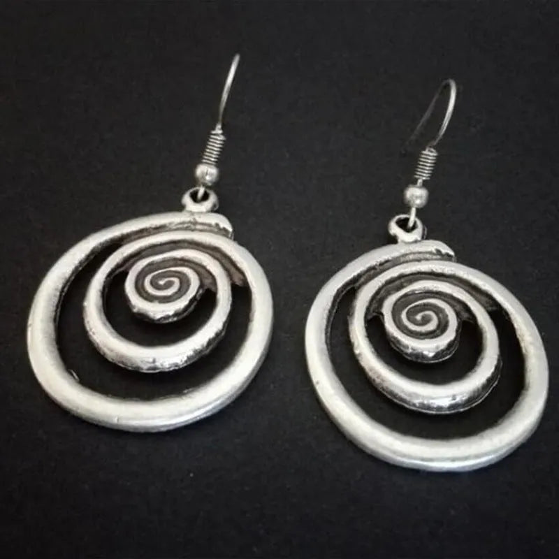 A pair of silver geometric spiral statement earrings with a distressed metal finish.