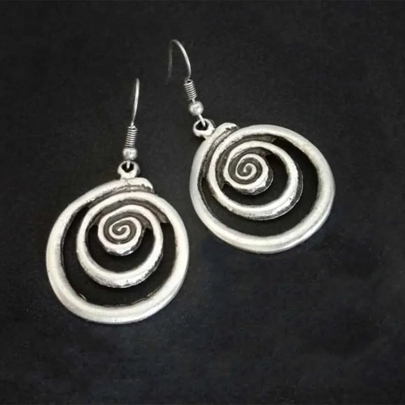 A pair of silver geometric spiral statement earrings with a distressed metal finish.