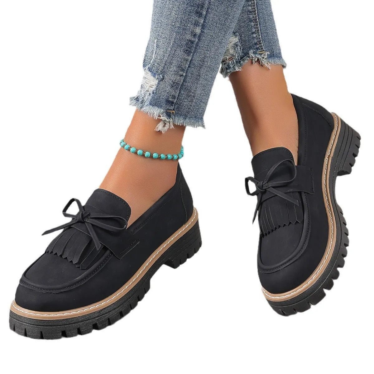 Black plus-size women's loafers with a bow and tassel decoration on the round toe.