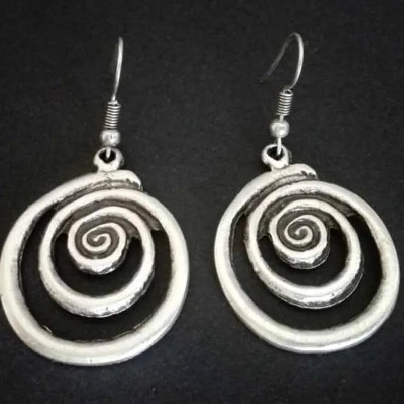 A pair of silver geometric spiral statement earrings with a distressed metal finish.