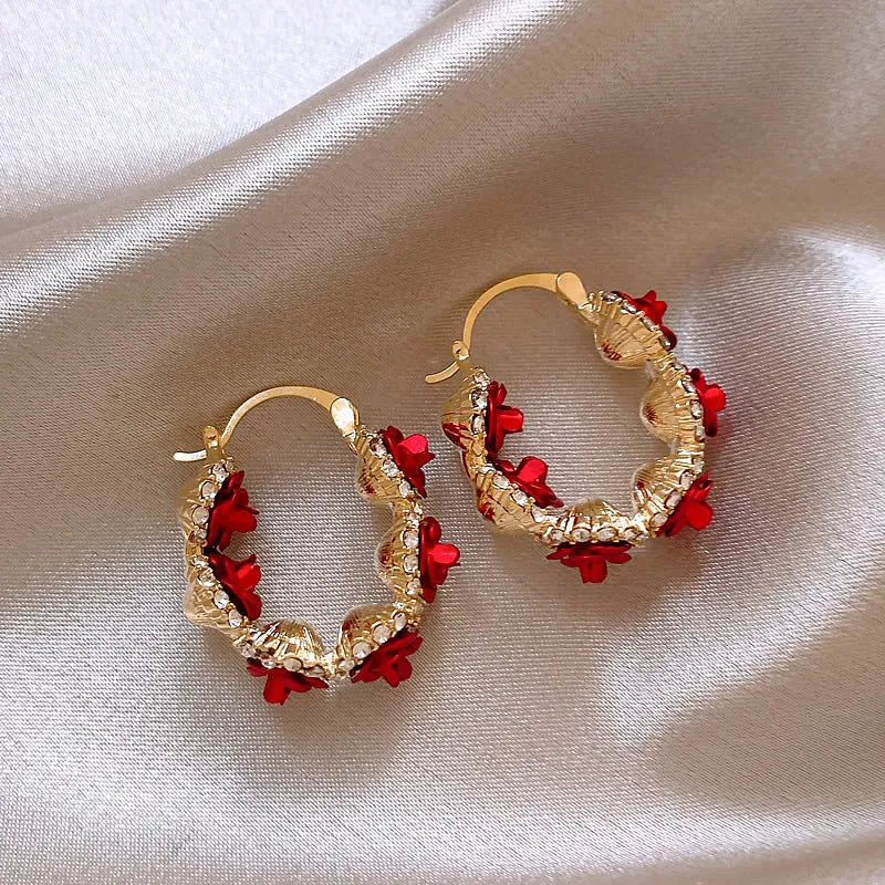 A pair of red flower-shaped alloy clip-on earrings with rose detailing for women.