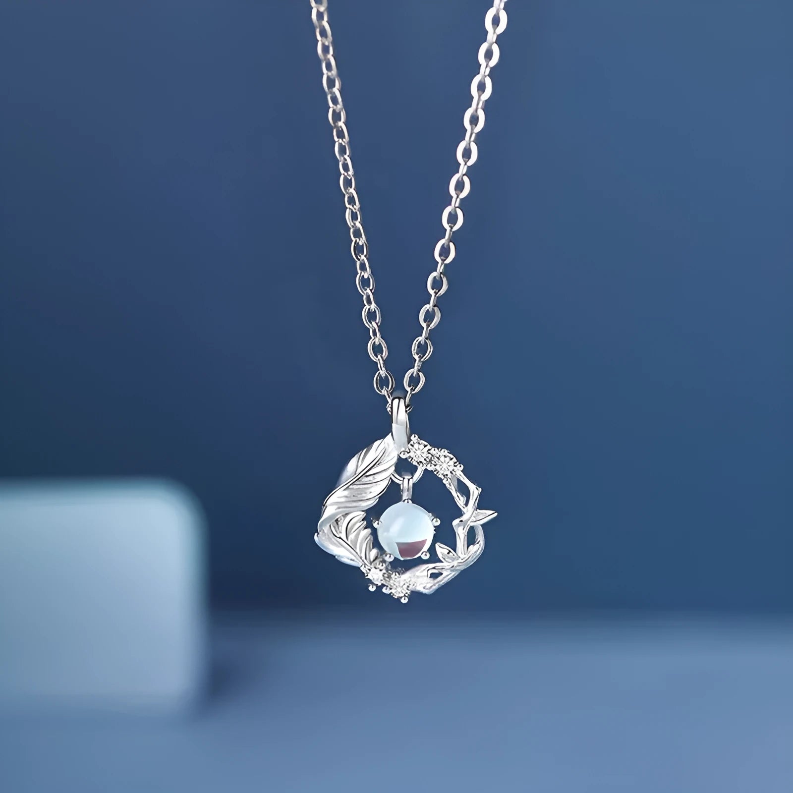 Geometric alloy pendant necklace with eucalyptus and bluebird design on adjustable chain.