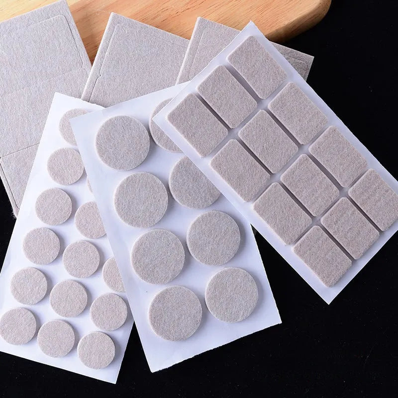 Beige plastic furniture protection foot pads in five different sizes on a wooden floor.