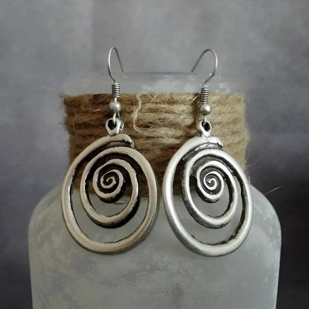 A pair of silver geometric spiral statement earrings with a distressed metal finish.