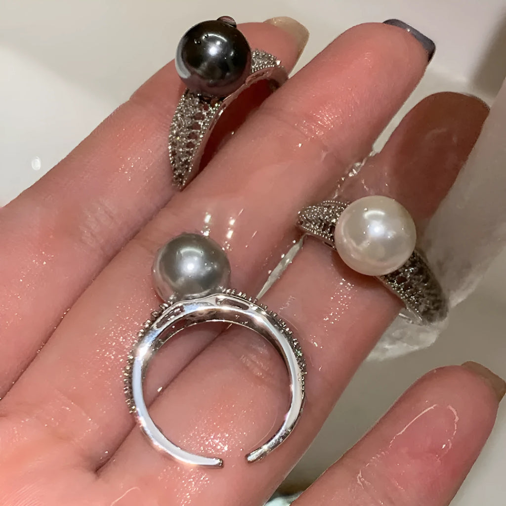 Silver-tone adjustable open ring with a geometric shape and a single black pearl on a model's finger.