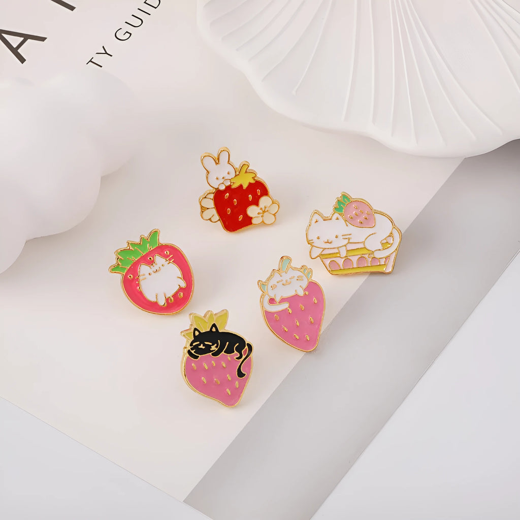 Close-up of a detailed alloy brooch showing a cute cat and strawberry in a dripping oil art style.