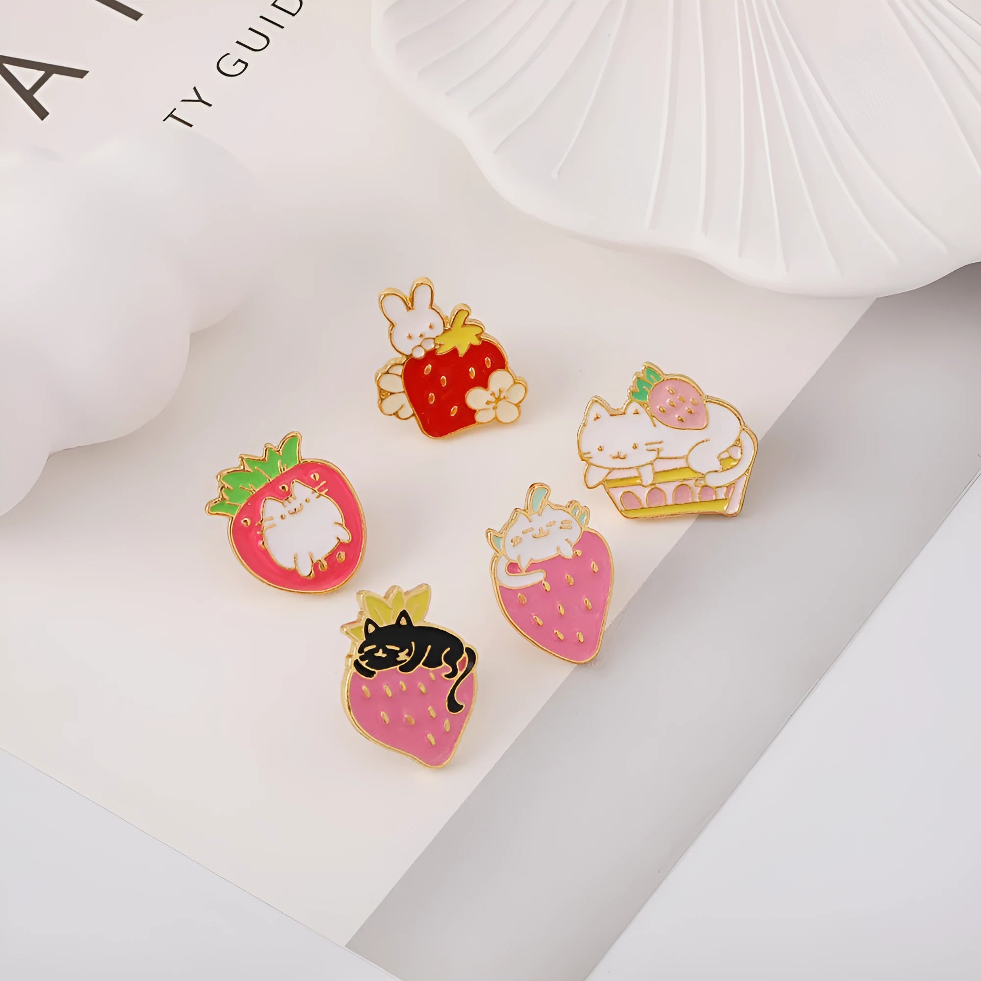 Close-up of a detailed alloy brooch showing a cute cat and strawberry in a dripping oil art style.