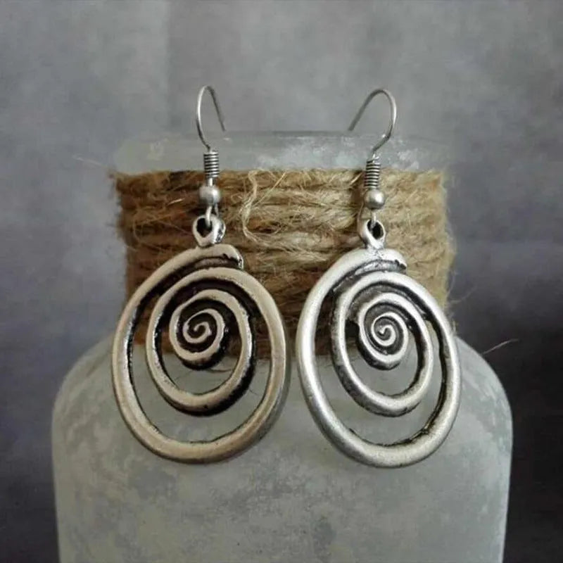 A pair of silver geometric spiral statement earrings with a distressed metal finish.