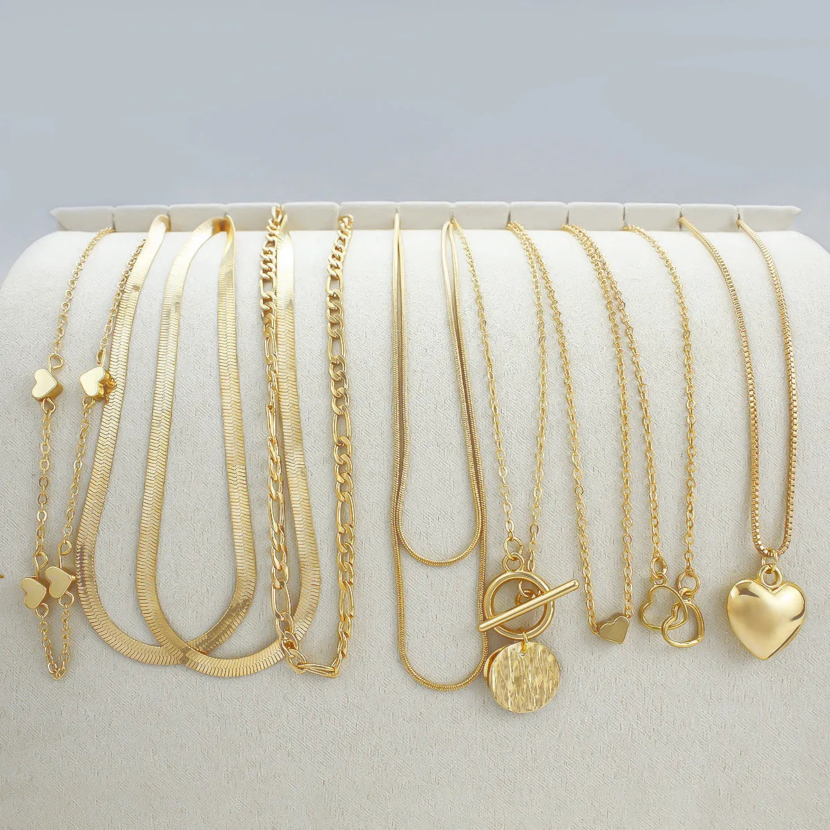Gold electroplated women's necklace suit with ten pieces showing alloy pendants on snake bone chains