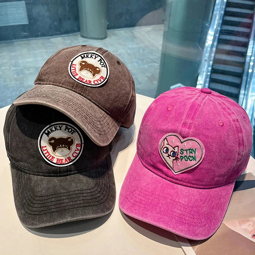 Two pink baseball caps with a cartoon love design, perfect for adding personality to your outfit.