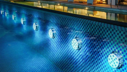 Colourful LED pool lights illuminating a backyard water feature at night