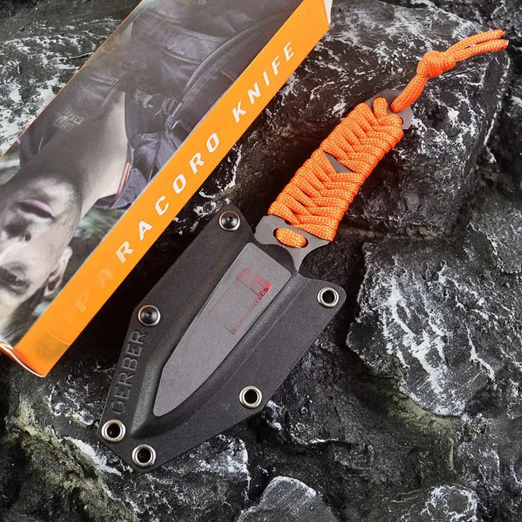Straight blade outdoor survival knife with binding rope handle next to ABS plastic sheath