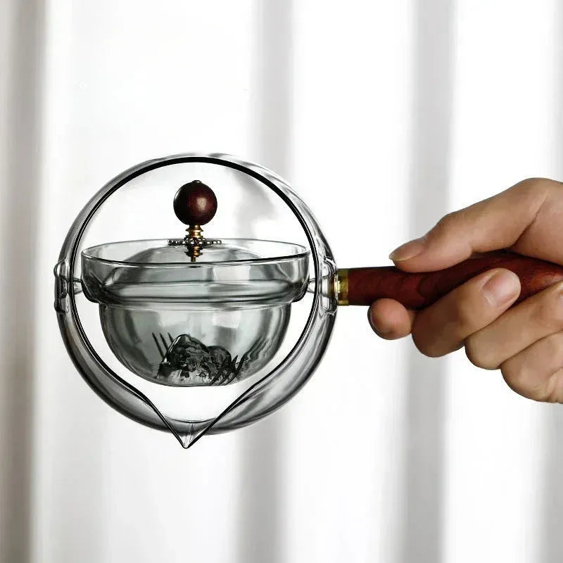 Transparent borosilicate glass teapot with wooden handle and infuser on rotary base