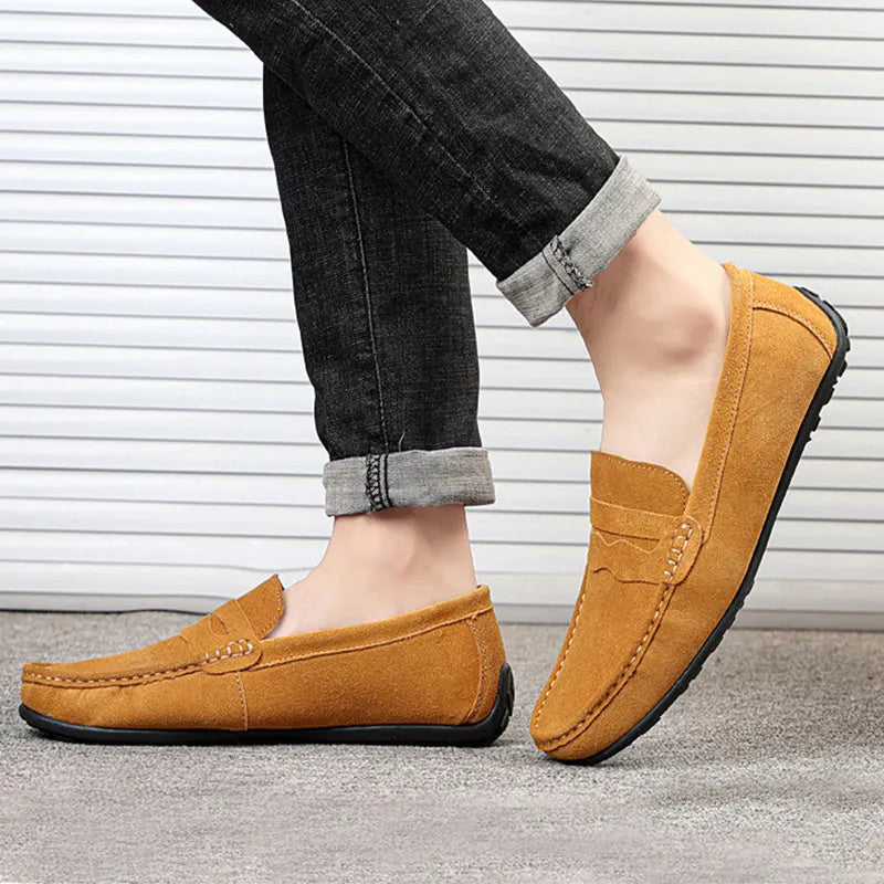 Men's brown suede slip-on loafers with round toe and flat rubber sole on a white background
