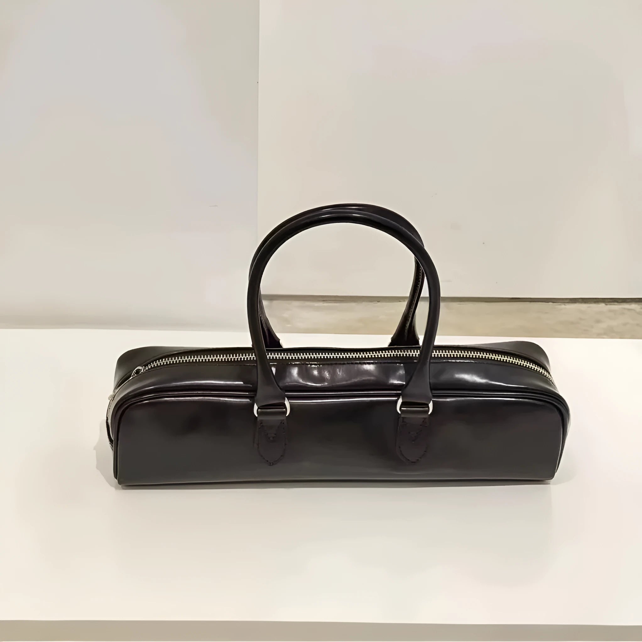 Black corduroy cowhide french stick underarm bag with sewing thread detail on a white background