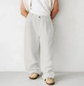 Man wearing loose grey linen-cotton jogger pants with pleated front, high waist, and straight leg.