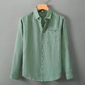 Loose long sleeve linen shirt in a cardigan style on a hanger, shown in light sapphire blue colour.