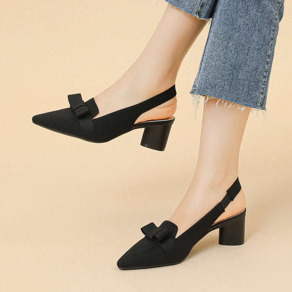 Women's black high heel sandals with closed pointed toe, decorative bow, and ankle buckle strap.