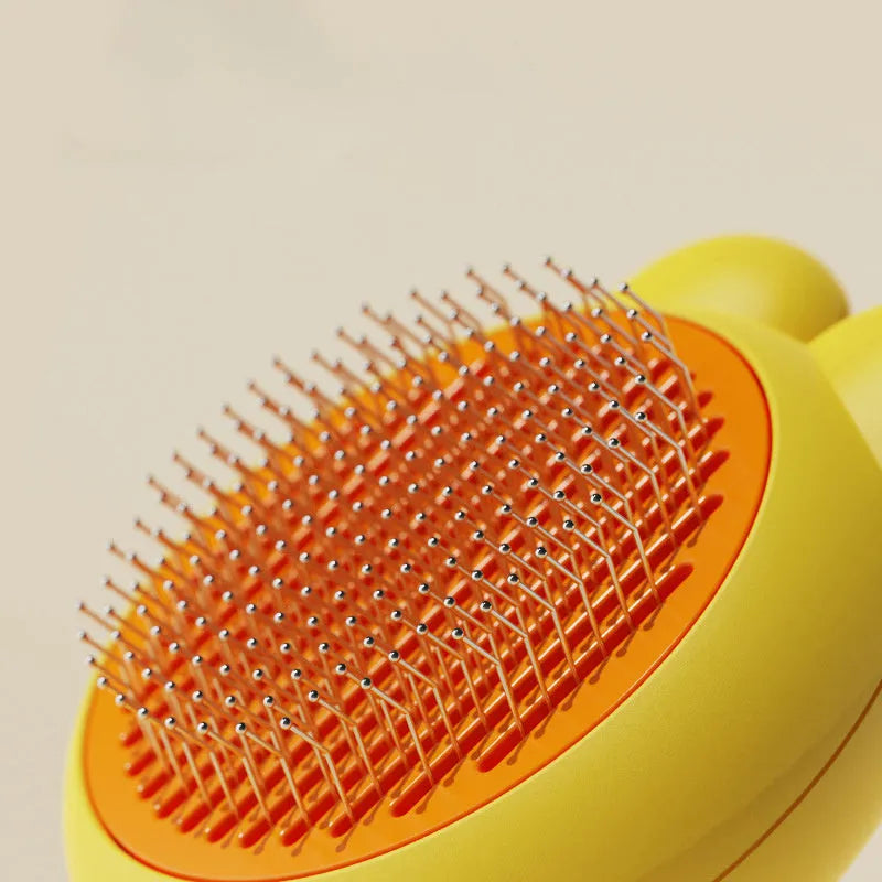 Self-cleaning pet brush with coloured comfort-grip handle and metal comb, shown with release button activated.
