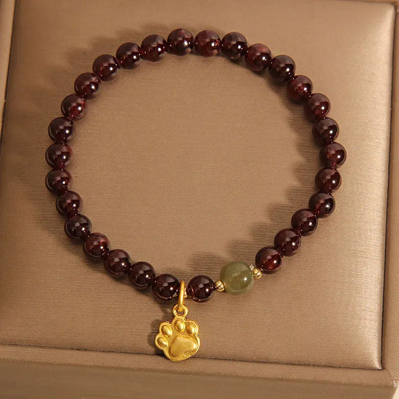 Women's crystal bracelet with a cat's paw garnet motif on a wrist.