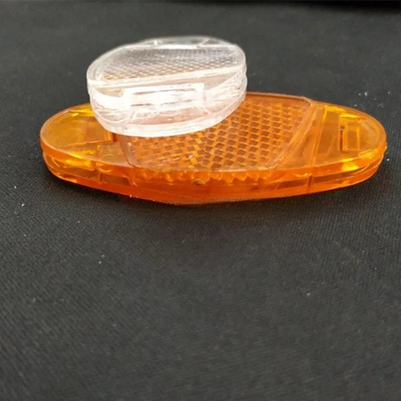 White and yellow plastic bicycle spoke reflectors for front and rear wheel safety.