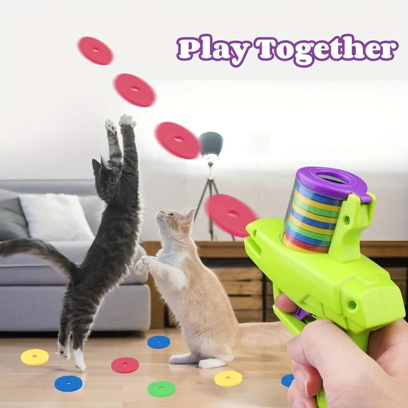 Green durable plastic manual cat toy launcher with a stack of soft foam discs on a floor.