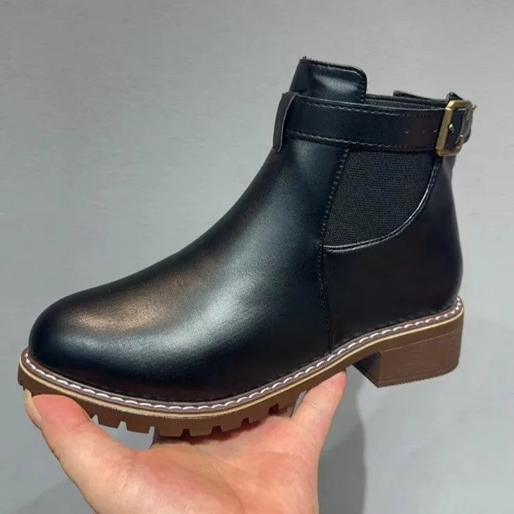 Women's round toe ankle boots with a belt buckle detail on the upper, shown in black.